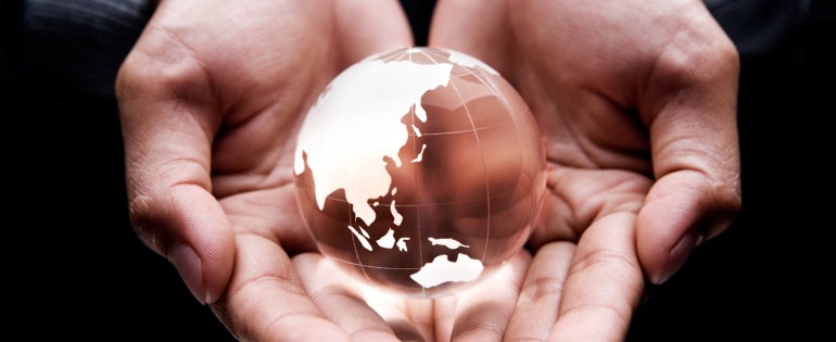 A small globe of the world is held in someone's hands
