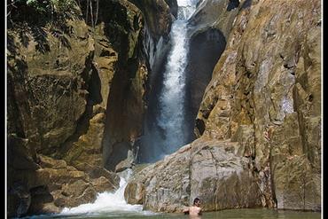 Person swimming at the bottom of a waterfall