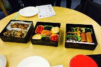 Three Japanese bento boxes with food on table