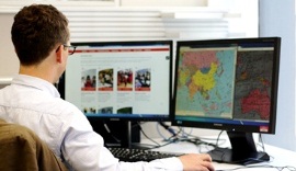A man studies a map on a desktop computer