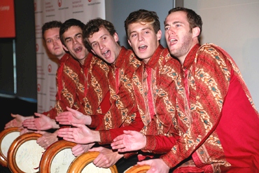 Five male drummers dressed in traditional red robes