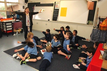 A teacher demonstrates a gesture to her class