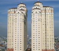 Two high-rise apartment buildings next door to each other, towering over the city below