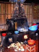 A stove with discarded coconut shells, pans, and bowls lying around during coconut toffee production