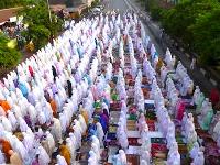 Hundreds of people congregating for a morning religious service, all dressed in colourful burqas
