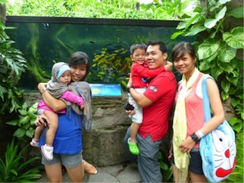 Devon's family at the zoo with two children and three adults standing in front of plants