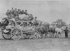 Black and white image of Chinese migrants on stagecoach led by horses