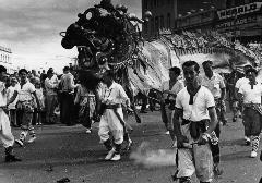 A black and white photograph of a parade with Chinese dragon