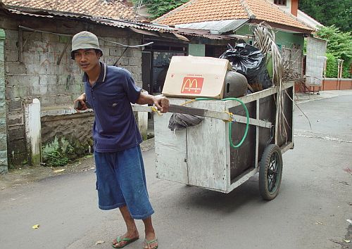 A man pulls a cart laden with rubbish down a street in Jakarta