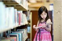 Young girl selecting a book from a library shelf