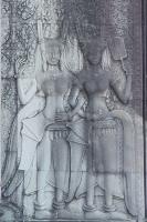 Bas-relief of two dancers with their arms linked wearing headdresses while one holds a fan