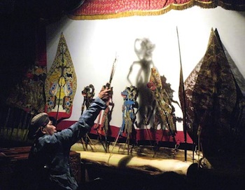 Puppet master manipulating wayang kulit puppets during a shadow-play performance in Jakarta